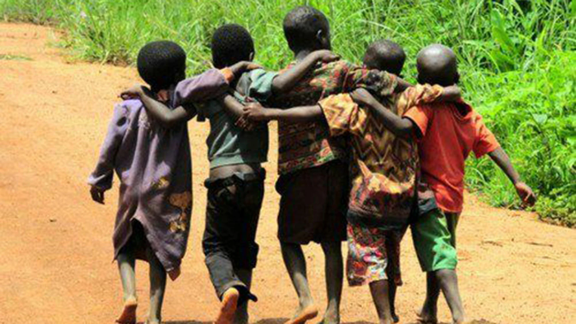 Infants caminant abraçats per un camí de terra